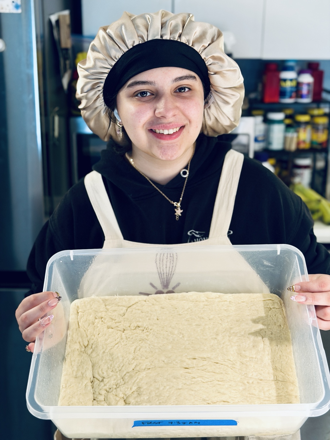 Jaiden, the baker behind Whisk & Wonder, holding a batch of cinnamon roll dough